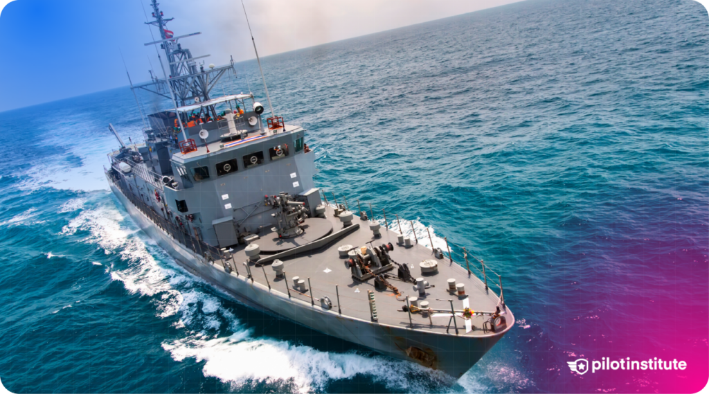 Military naval vessel cruising through the ocean, creating a wake as it moves.